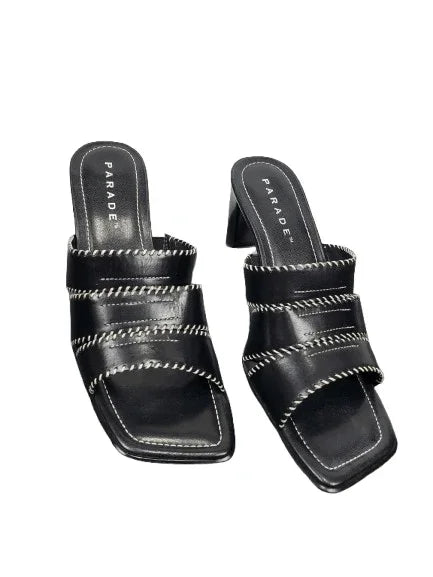 Black high-heeled sandals with decorative straps on a white background
