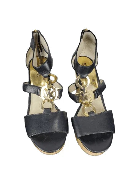 Pair of black high-heeled sandals with gold accents on a white background