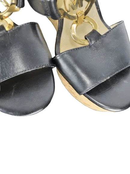 Black sandals with gold straps on a white background