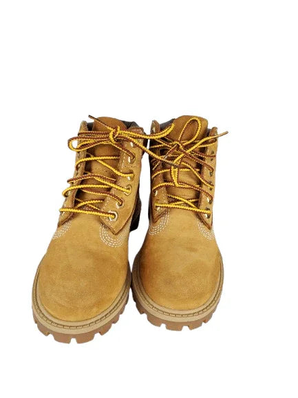 Pair of tan boots with yellow laces on a white background