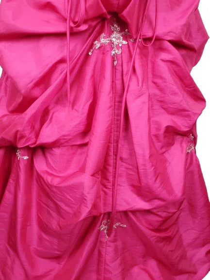 Close-up of a pink dress with ruffled details and decorative elements on a white background