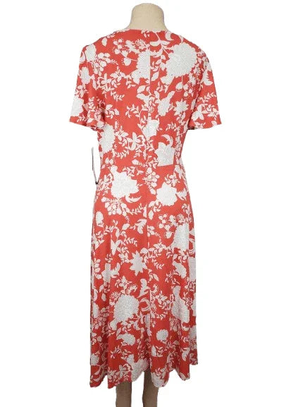Coral dress with white floral pattern on a mannequin against a white background