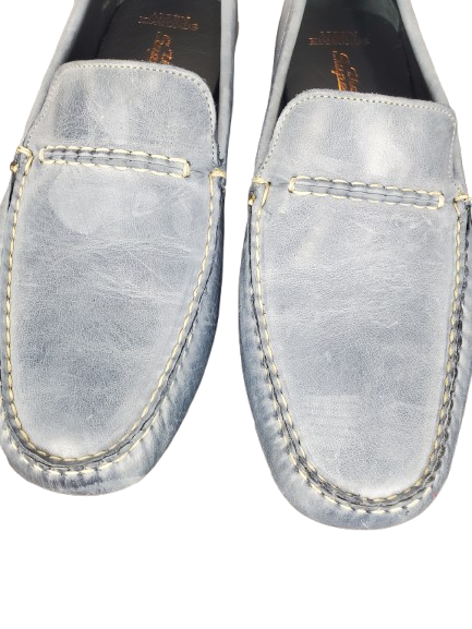 Pair of light blue loafers with gold stitching on a white background