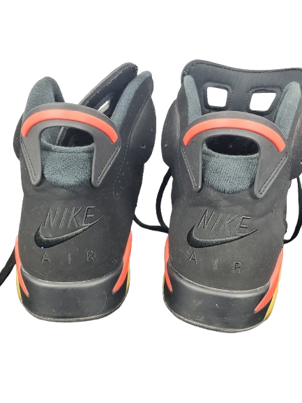 Pair of black Nike Air shoes with orange accents on a white background