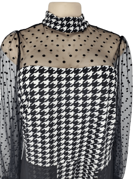 Black and white checkered jumpsuit with sheer sleeves on a mannequin against a white background