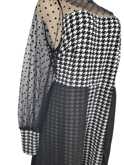 Black and white houndstooth patterned dress with sheer polka dot sleeves on a white background