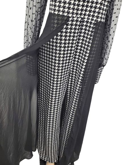 Black and white checkered jumpsuit with sheer sleeves on a mannequin against a white background