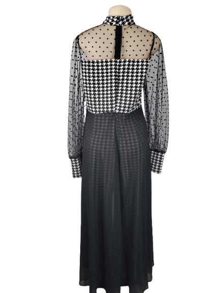 Black and white checkered jumpsuit with sheer sleeves on a mannequin against a white background
