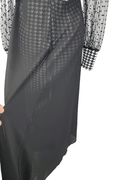 Black and white checkered jumpsuit with sheer sleeves on a mannequin against a white background