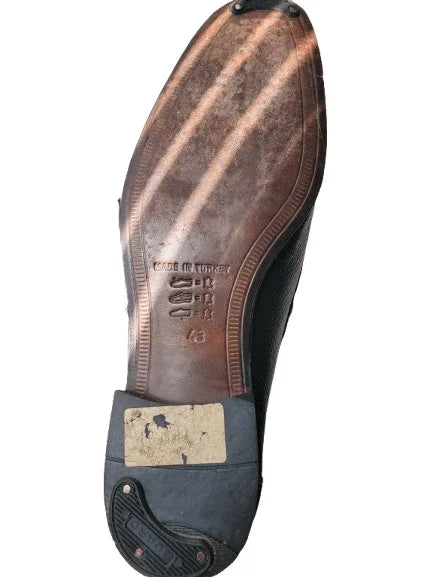 Close-up of a worn shoe sole with visible wear and a label on a white background