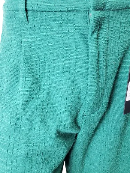 Close-up of teal textured fabric with a tag on a white background