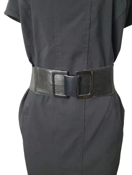 Person wearing a black belt with a large buckle on a plain background