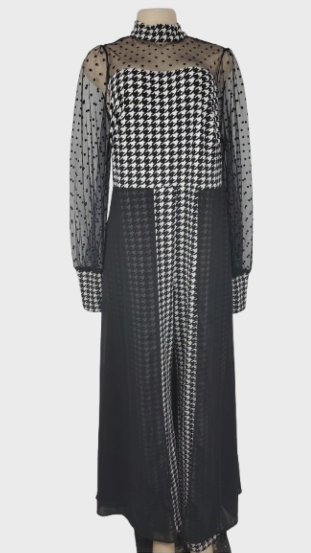 Black and white checkered jumpsuit with sheer sleeves on a mannequin against a white background