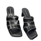 Black high-heeled sandals with decorative straps on a white background