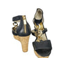 Black wedge sandals with cork sole and gold accents on a white background