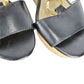 Black sandals with gold straps on a white background