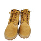 Pair of tan boots with yellow laces on a white background