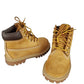 Pair of tan boots with brown accents on a white background