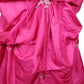 Close-up of a pink dress with ruffled details and decorative elements on a white background
