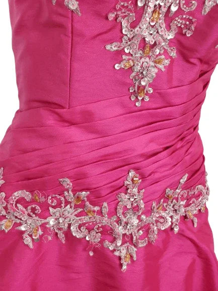 Close-up of a pink dress with intricate silver and crystal embellishments on a white background
