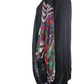 Black sweater with colorful pattern on sleeve on a mannequin against a white background