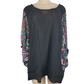 Black oversized shirt with colorful sleeves on a mannequin against a white background