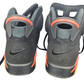 Pair of black Nike Air shoes with orange accents on a white background