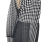 Black and white houndstooth patterned dress with sheer polka dot sleeves on a white background