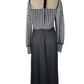 Black and white checkered jumpsuit with sheer sleeves on a mannequin against a white background