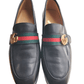 Black leather loafers with a colorful striped buckle on a white background