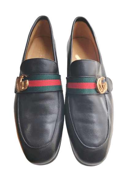 Black leather loafers with a colorful striped buckle on a white background