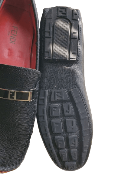 Black loafers with a prominent brand logo on a white background