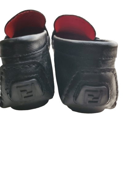 Pair of black leather shoes with red lining on a white background