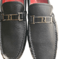 Black loafers with gold logo detail on a white background