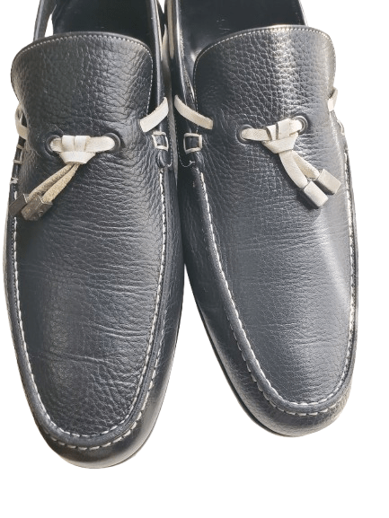 Pair of navy loafers with decorative bows on a white background