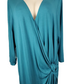 Teal dress with a deep neckline and knot detail on a mannequin against a white background