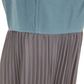Close-up of a blue top and pleated gray skirt