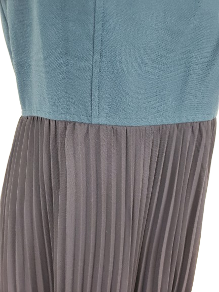 Close-up of a blue top and pleated gray skirt