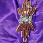 Decorative brooch with wooden-like design and rhinestones on a purple fabric background