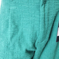 Close-up of teal textured fabric with a tag on a white background