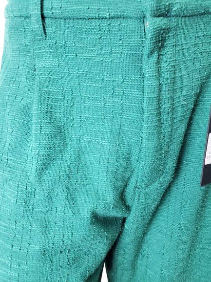 Close-up of teal textured fabric with a tag on a white background
