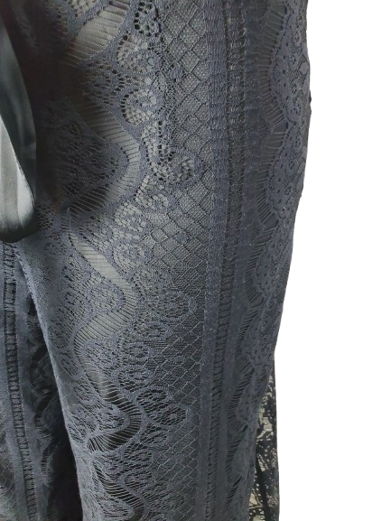 Close-up of a black lace fabric with intricate patterns on a white background