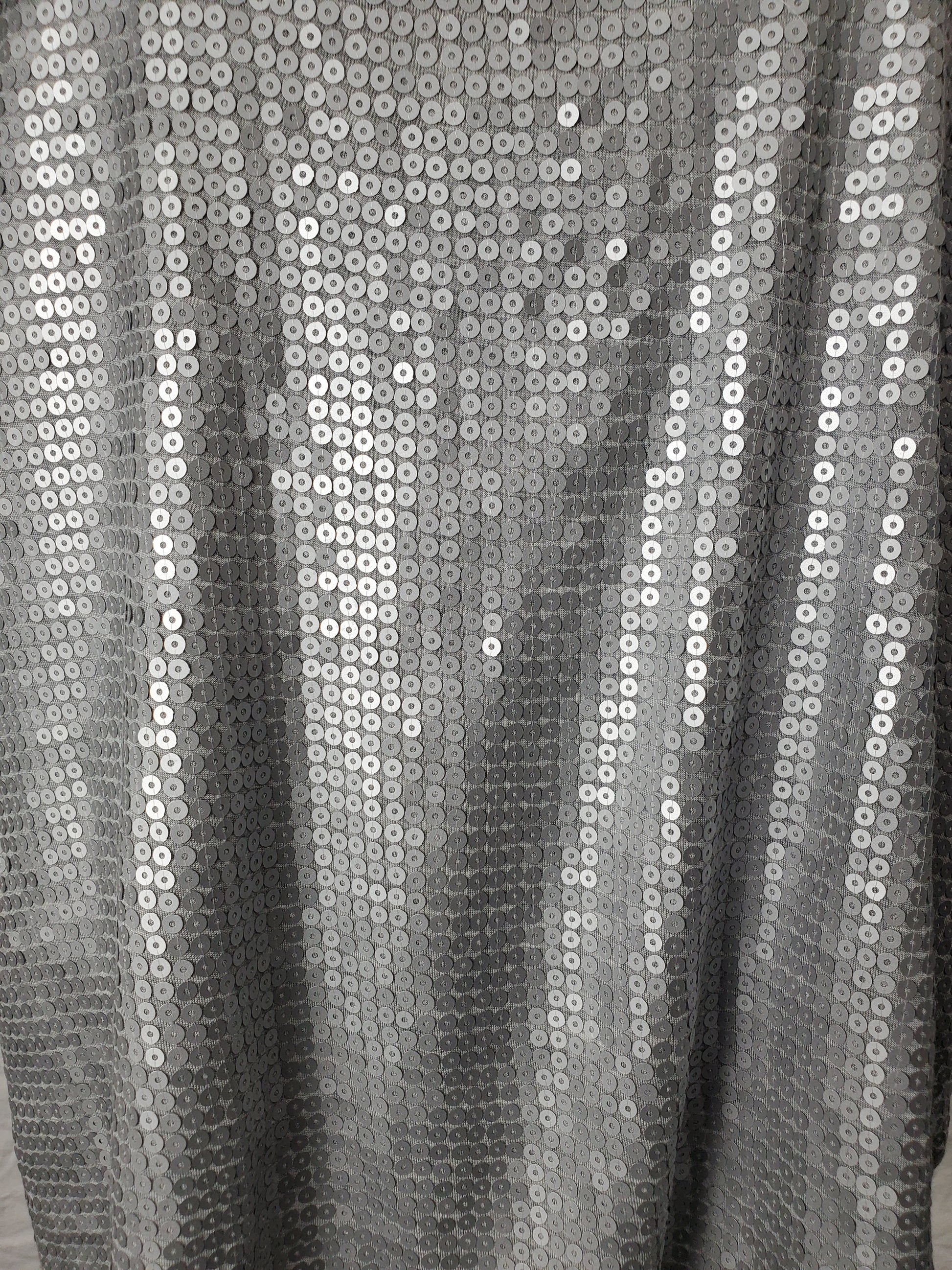 Close-up of silver sequin fabric with a black background