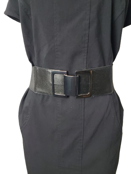 Person wearing a black belt with a large buckle on a plain background