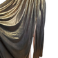 Gold and black draped fabric on a mannequin against a white background