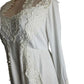 White lace-trimmed garment on a mannequin with a plain background