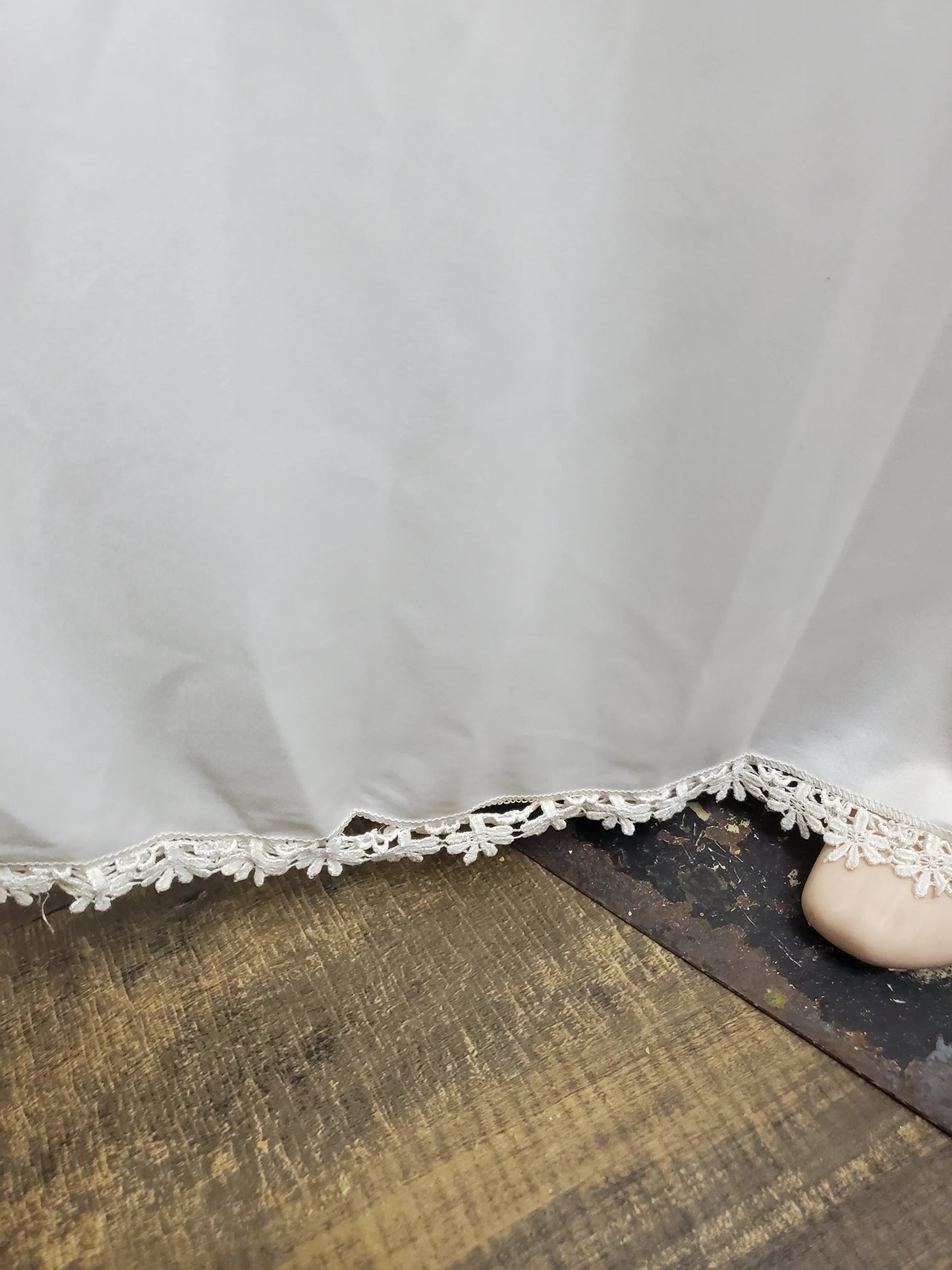 Close-up of a white lace trim on a wooden surface with a stone.