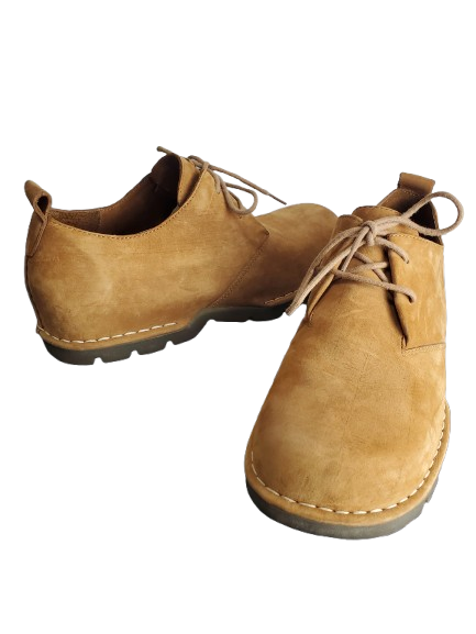 Pair of tan suede shoes with laces on a white background