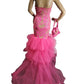 Mannequin wearing a pink evening gown with a matching handbag on a white background