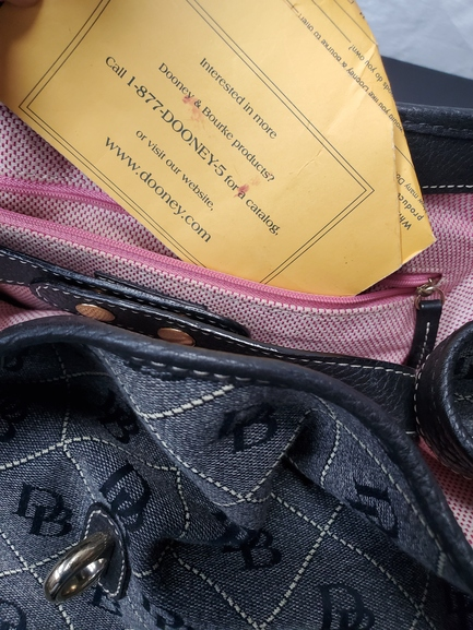 Close-up of a black leather bag with visible branding, pink zipper, and yellow tag.